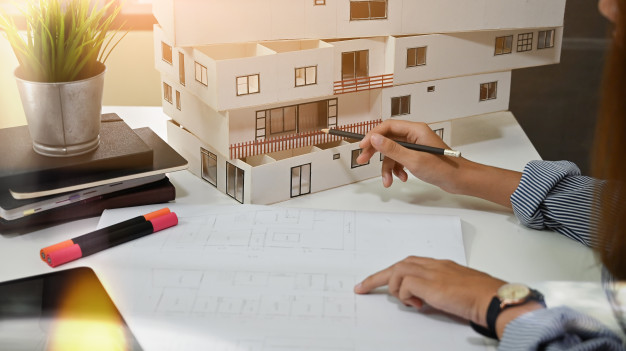 female-architect-working-with-model-house-blueprint-home-office